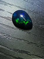 Pear-shaped black opal cabochon showing green and blue fire