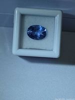 Oval blue fluorite in display box under cool light