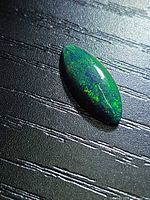 Top view of marquise black opal showing green play of color