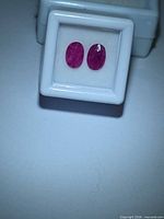 Pair of oval rubies in white gem box, overhead view