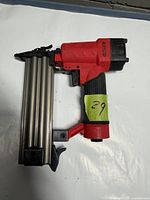 Left side view of Airco red/black brad nailer showing grip, trigger and magazine