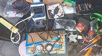 Overall lot showing charger, power strips, cooler, brake pads, ratchet strap, tools, cords