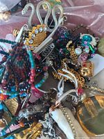 Tangled pile showing snake brooch, beaded bracelets, chains