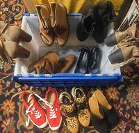 Overview of tote with nine pairs of shoes including boots, flats, sneakers, slides