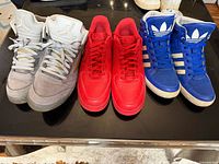 Front view of three pairs: grey Air Jordan 5, red Air Force 1, blue Adidas high-top
