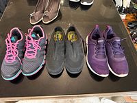 Three pairs of women’s sneakers on table