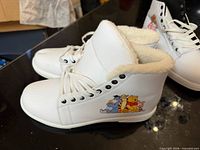 White high-top sneaker with Winnie the Pooh characters, fleece lining visible