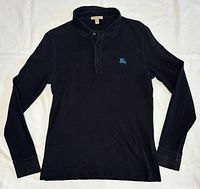 Full view of black long-sleeve polo shirt laid flat