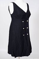 Front view of black sleeveless dress showing double-breasted jeweled buttons