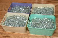 Four storage bins filled with iridescent clear glass pebbles on wood floor