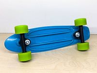 Full underside view of blue plastic mini skateboard with green wheels