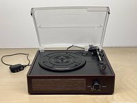 Record player open showing platter, tonearm, power adapter