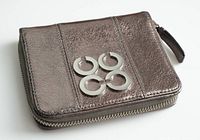 Front angled view showing pewter metallic leather exterior, zip-around design, and interlocking C logo hardware