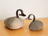 Both stone and steel duck sculptures, front angle