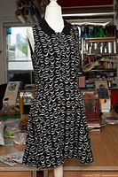 Front view of black sleeveless dress with white bow print on mannequin