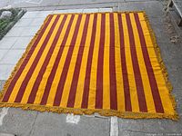 Full view of golden yellow and maroon striped rug laid flat showing overall pattern and size