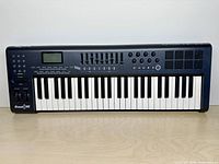 Front view showing full keyboard, sliders, knobs, pads and LCD