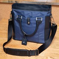 Front view of navy ballistic nylon tote with black leather trim, top handles, shoulder strap attached