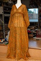 Front view of full-length orange and green paisley cotton mumu on mannequin