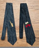 Both embroidered cotton ties laid flat showing full length and motifs