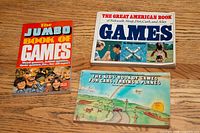 Three vintage children's game books displayed on wooden surface