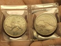 Fronts of both coins in plastic flips: UK 10 pence crowned lion and Irish florin salmon design