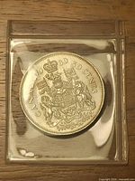 Reverse of 1980 Canadian 50-cent coin in holder showing Coat of Arms