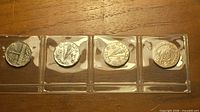 Four coins in plastic 2×2 holders on strip