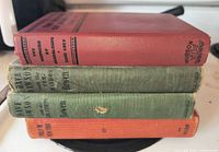 Stack of four clothbound books showing topmost red cover and side wear