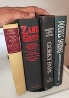 Spine view of four hardcover books showing titles and authors