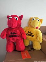 Front view of red and yellow Hostess Munchies plush figures standing on box