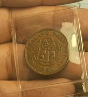 Reverse of 1945 New Zealand half penny in holder, tiki design visible