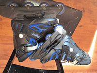 Left side view of both black and blue Stinger inline skates showing wheels and boot detail