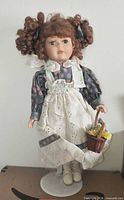 Full view of porcelain doll on stand holding basket