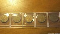 Front view of five UK 2 pence coins in plastic strip
