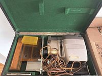 Open case showing projector with power cord and slide magazines