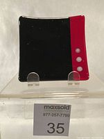 Front view of fused glass dish showing black and red sections with white dots