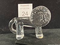 Front view of clear glass lion figurine showing full form and label