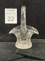 Front view of clear pressed crystal bridal basket showing handle, scalloped rim, etched floral design, starburst base