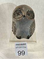 Front view of grey stoneware owl on stand showing eyes and textured wings