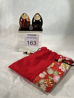 Full lot showing both dolls on base with kinchaku pouch