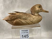 Right side profile of carved wooden duck decoy showing overall form, feather carving and glass eye