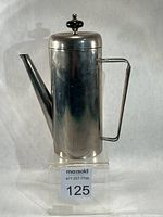 Front view showing overall form, handle, spout and lid