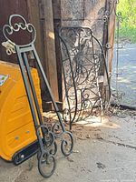 Black wrought iron easel, black rack, glimpse of cream trellis