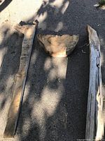 All three wood pieces laid out on pavement: two beams and one wedge chunk