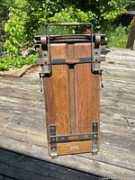 Full front view of upright oak trouser press with metal hardware