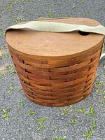 Closed basket showing woven wood slats, lid, and suede strap