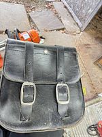 front view of one saddle bag showing flap, buckles, stitching and yellow brand tag