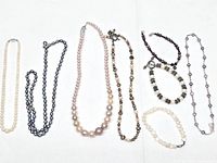 Eight pearl jewelry pieces laid out, highlighting three necklaces with sterling clasps