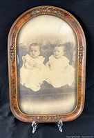 Front view showing sepia photo of two infants in carved burl frame